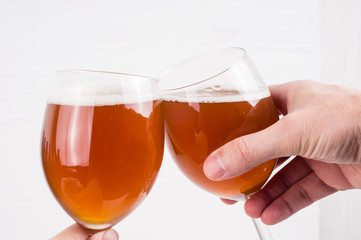 two hands holding a glass of homemade craft beer on white background.  Ale or lager from pilsner malt