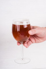 male hand holding a glass of homemade craft beer on white background.  Ale or lager from pilsner malt