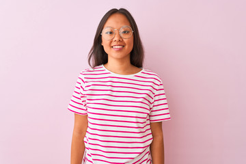 Fototapeta premium Young chinese woman wearing striped t-shirt and glasses over isolated pink background with a happy and cool smile on face. Lucky person.