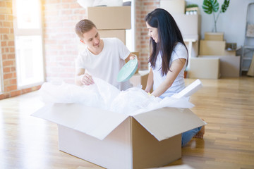 Obraz premium Young beautiful couple open cardboard boxes to order new home
