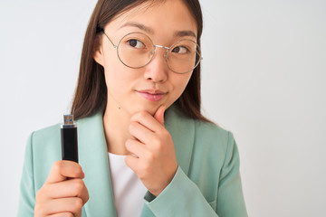 Young chinese businesswoman holding usb memory over isolated white background serious face thinking...