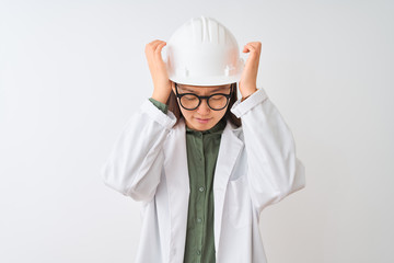 Young chinese engineer woman wearing coat helmet glasses over isolated white background suffering from headache desperate and stressed because pain and migraine. Hands on head.