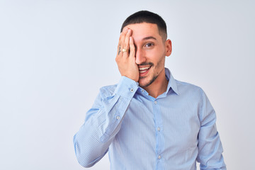 Young handsome business man standing over isolated background covering one eye with hand, confident smile on face and surprise emotion.