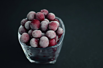 frozen red cherries closeup in glass on black background