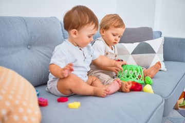 Beautiful toddlers sitting on the sofa playing with toys at home