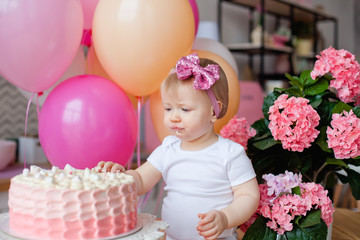 Fototapeta na wymiar a little girl got dirty with cake and colorful balloons for her birthday. crash cake