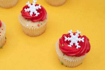 White cupcakes with red icing on a yellow background