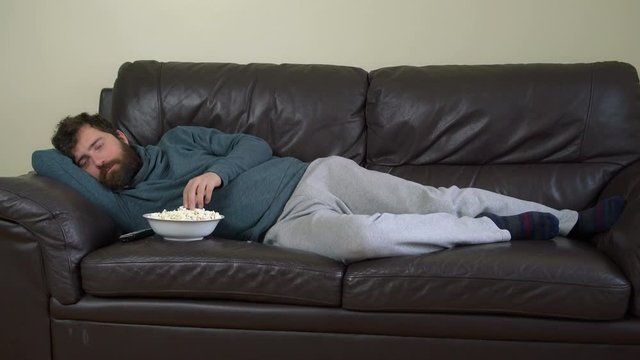 Man Lying on Leather Couch and Watching Tv with Popcorn