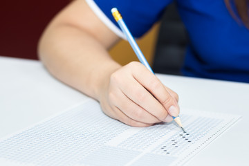 Student filling out answers to blue answer sheet with blue pencil.