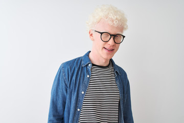 Young albino blond man wearing denim shirt and glasses over isolated white background winking looking at the camera with sexy expression, cheerful and happy face.