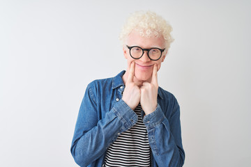 Young albino blond man wearing denim shirt and glasses over isolated white background Smiling with open mouth, fingers pointing and forcing cheerful smile