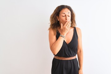Middle age woman wearing black casual dress standing over isolated white background bored yawning tired covering mouth with hand. Restless and sleepiness.