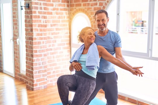 Middle age beautiful sporty couple smiling happy. Standing with smile on face hugging at gym - Powered by Adobe