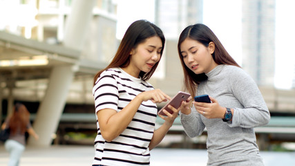 Two Teenager travellers checking map on smartphone in city