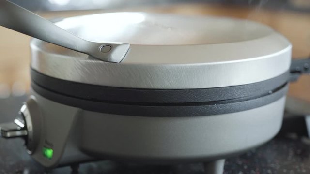 Making homemade waffles in an electric waffle maker.