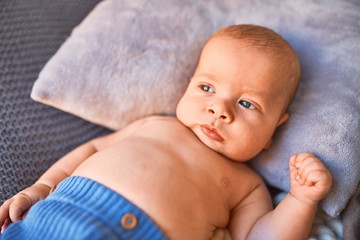 Adorable baby lying down on the sofa over blanket at home. Newborn relaxing and resting comfortable