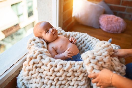 Adorable baby lying down on the floor over blanket at home. Newborn relaxing and resting comfortable