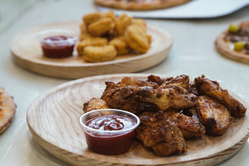 Close-up of chicken wings cap with ketchup sauce on wooden plate.