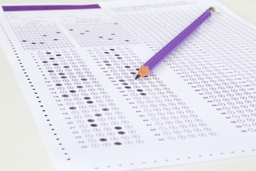 Student filling out answers to purple answer sheet with purple pencil.