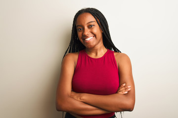 Obraz premium African american woman wearing red casual t-shirt standing over isolated white background happy face smiling with crossed arms looking at the camera. Positive person.