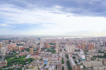 Fototapeta na wymiar Aerial view of the landscape in a big city with high houses and skyscrapers in the center of Novosibirsk under a beautiful blue sky with clouds on a summer cloudy day.