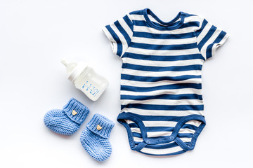 Blue bodysuit for baby boy near children's accessories on white background top-down copy space