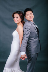 Young asian groom and bride posing and smiling in studio for pre-wedding shot