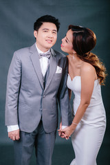 Young asian groom and bride posing and smiling in studio for pre-wedding shot