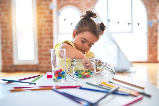 Beautiful toddler standing playing with chocolate colored balls on the table at kindergarten