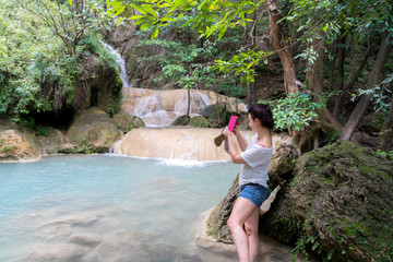 young cute hipster girl travelling at beautiful Erawan waterfall mountains  green forest hiking views at Kanchanaburi, Thailand. guiding  idea for female backpacker woman women backpacking