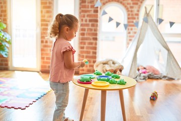 Beautiful blond toddler girl playing  meals using plastic food at kindergarten