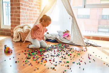 Beautiful blond toddler girl playing with constuction blocks outside tipi at kindergarten © Krakenimages.com