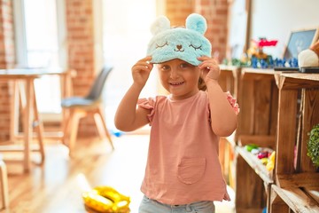 Beautiful blond toddler girl wearig sleep animal mask standing at kindergarten