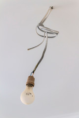 A temporary light bulb on a wire during repair close-up.