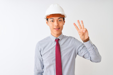 Chinese architect man wearing tie and helmet standing over isolated white background showing and pointing up with fingers number three while smiling confident and happy.