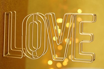 Love concept. Valentine's Day. Word LOVE golden letters on a yellow background with golden bokeh.