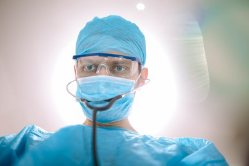 Doctor male surgeon in uniform working with a stethoscope in a medical office.