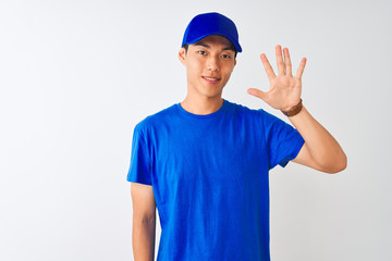 Chinese deliveryman wearing blue t-shirt and cap standing over isolated white background showing and pointing up with fingers number five while smiling confident and happy.