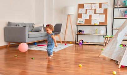 Beautiful caucasian infant playing with toys at colorful playroom. Happy and playful with pink baloon at kindergarten.