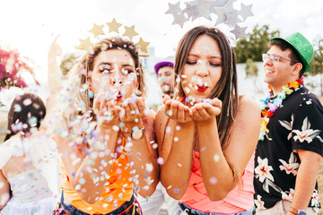 Brazilian Carnival. Young women in costume enjoying the carnival party blowing confetti