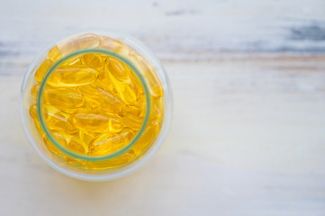 Top view pile of capsules Omega 3 in glass bottle on wood table