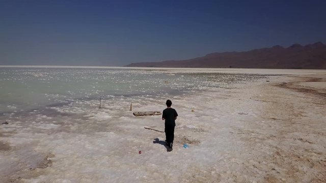 One man man walking lonely on white Urmia salt lake, Iran