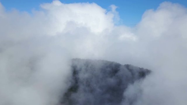 Peak of foggy green mountains and cloudscape under blue sky