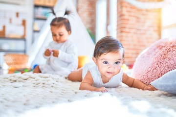 Fototapeta premium Beautiful infant happy girls playing together at home kindergarten lying on blanket