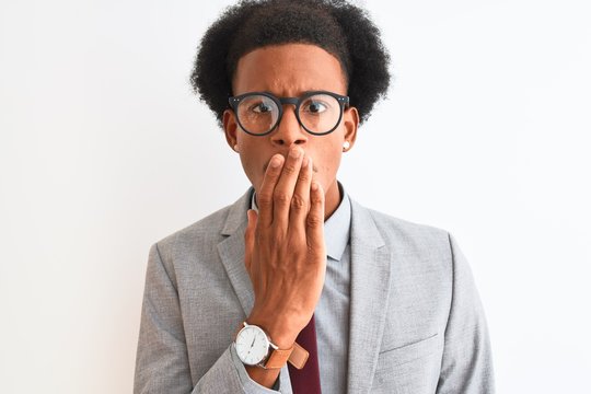 Young african american businessman holding dollars standing over isolated white background cover mouth with hand shocked with shame for mistake, expression of fear, scared in silence, secret concept