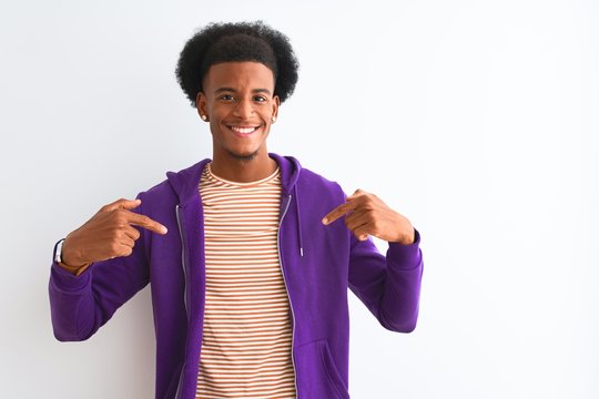 African american man wearing purple sweatshirt standing over isolated white background looking confident with smile on face, pointing oneself with fingers proud and happy.