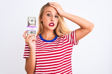 Obraz premium Beautiful woman wearing red striped t-shirt holding dollars over isolated white background stressed with hand on head, shocked with shame and surprise face, angry and frustrated. Fear and upset 
