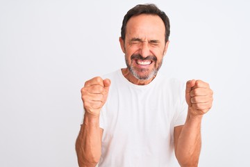 Middle age handsome man wearing casual t-shirt standing over isolated white background excited for success with arms raised and eyes closed celebrating victory smiling. Winner concept.