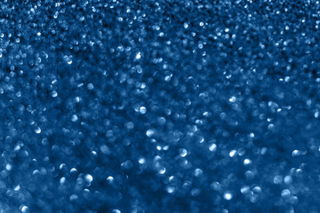 Blue background with glitter. Shining flare, lens bokeh. Classic trendy color.