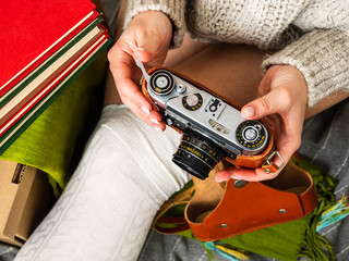 Girl sitting on the floor surrounded by books and holding a retro camera